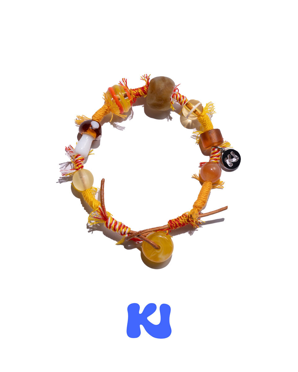 Braided beaded bracelet with amber and brown glass beads, orange fringe tassels.