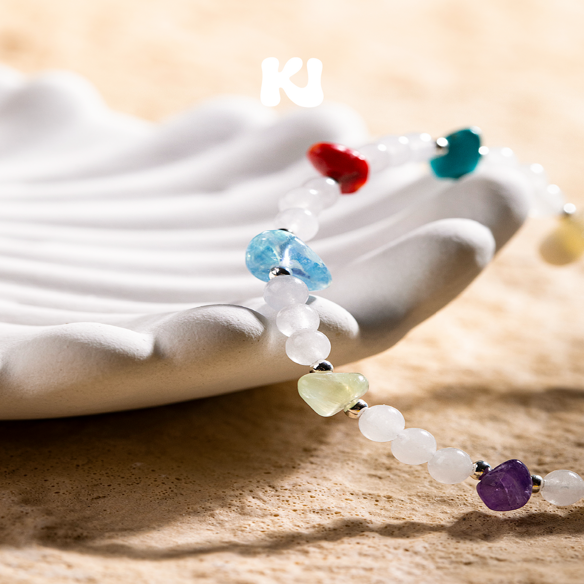 Beaded bracelet with white beads and multicolor gemstone accents on fabric