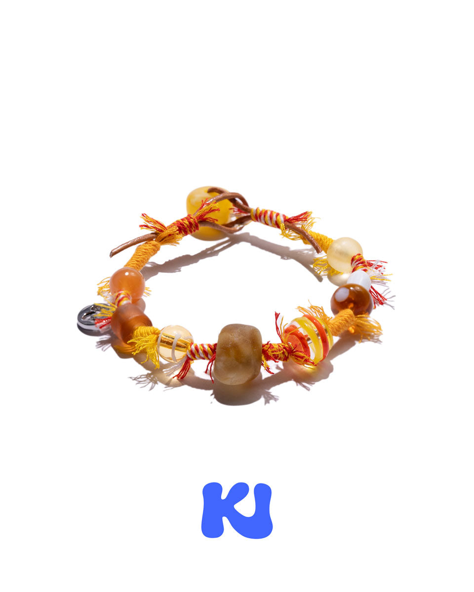 Beaded bracelet with braided cord, mixed amber and white beads, and small charm.