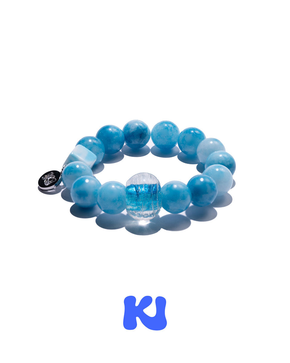Blue beaded bracelet with round beads, charm, and clear centerpiece bead