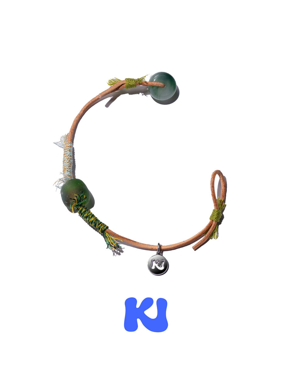 Moss Glade charm bracelet with green beads, braided cord, and round metal tag