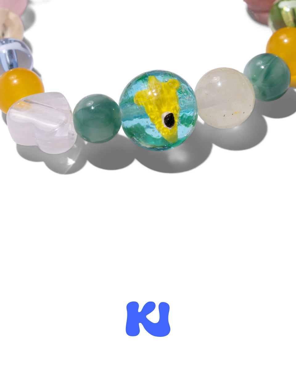 Beaded crystal bracelet featuring fish-eye charm between green and white beads