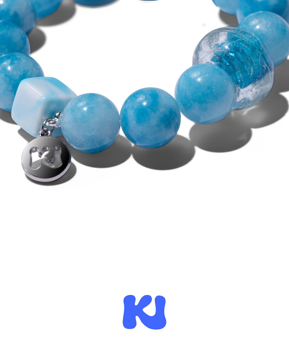 Blue beaded bracelet close-up with silver charm and frosted blue round beads