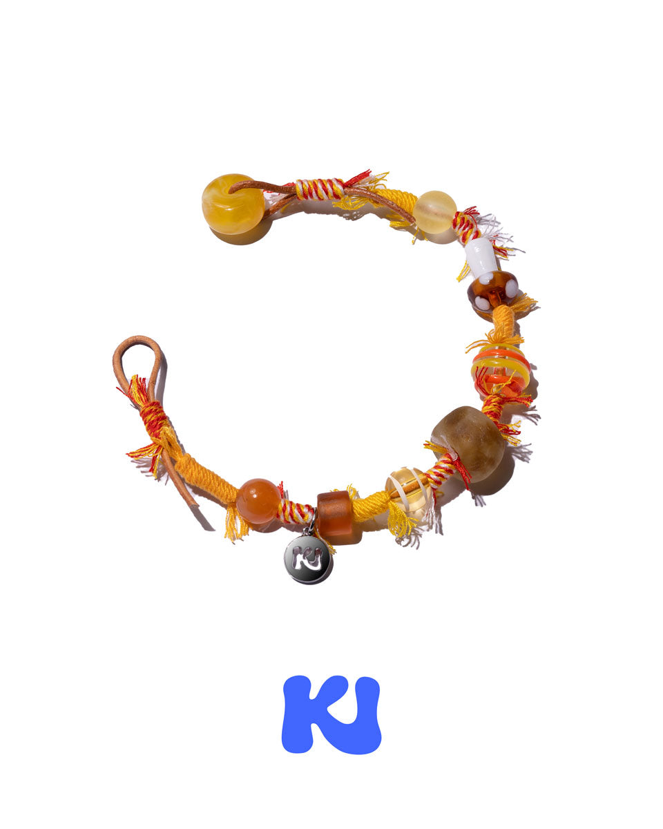 Braided bracelet with round beads and knot accents, including dark bead charm.