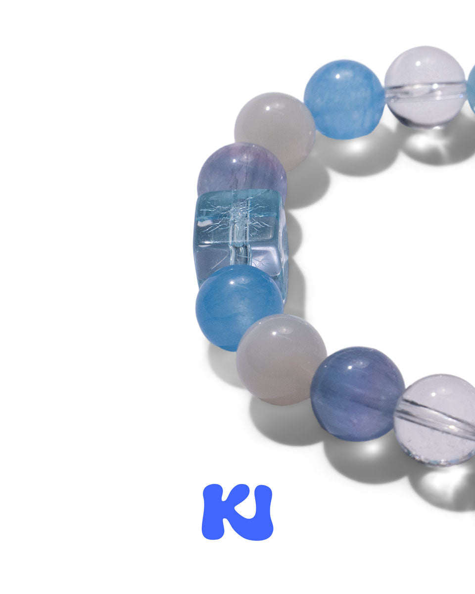 Beaded bracelet with blue, gray, and clear stones, featuring an etched rectangular bead