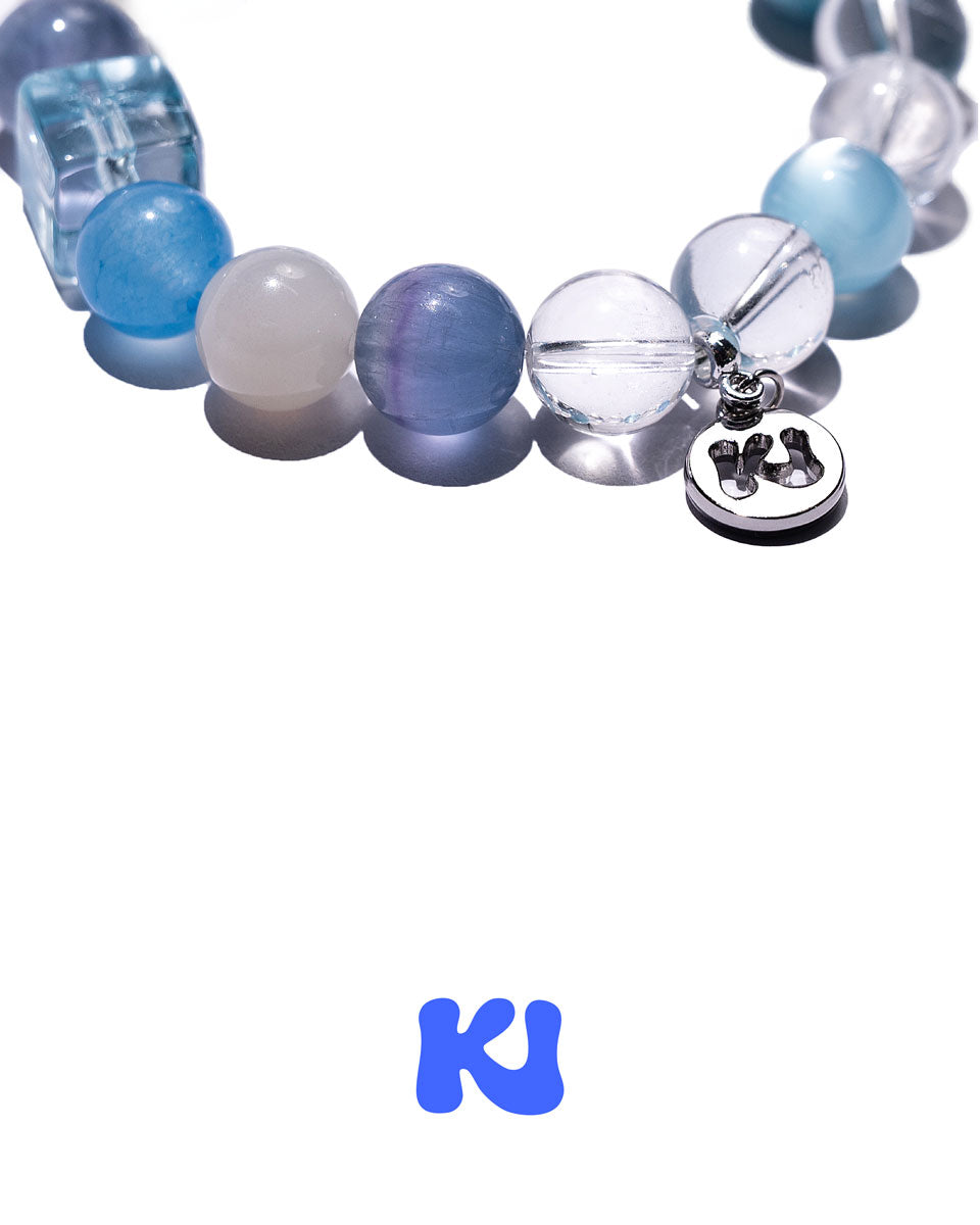 Close-up of blue and clear beaded bracelet with two metal charm pendants