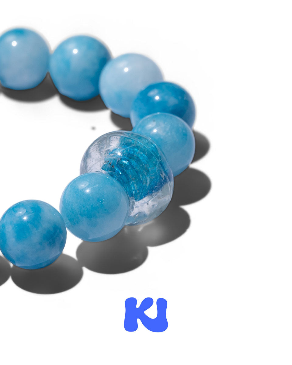 Blue bead bracelet detail with clear spacer beads and silver charm