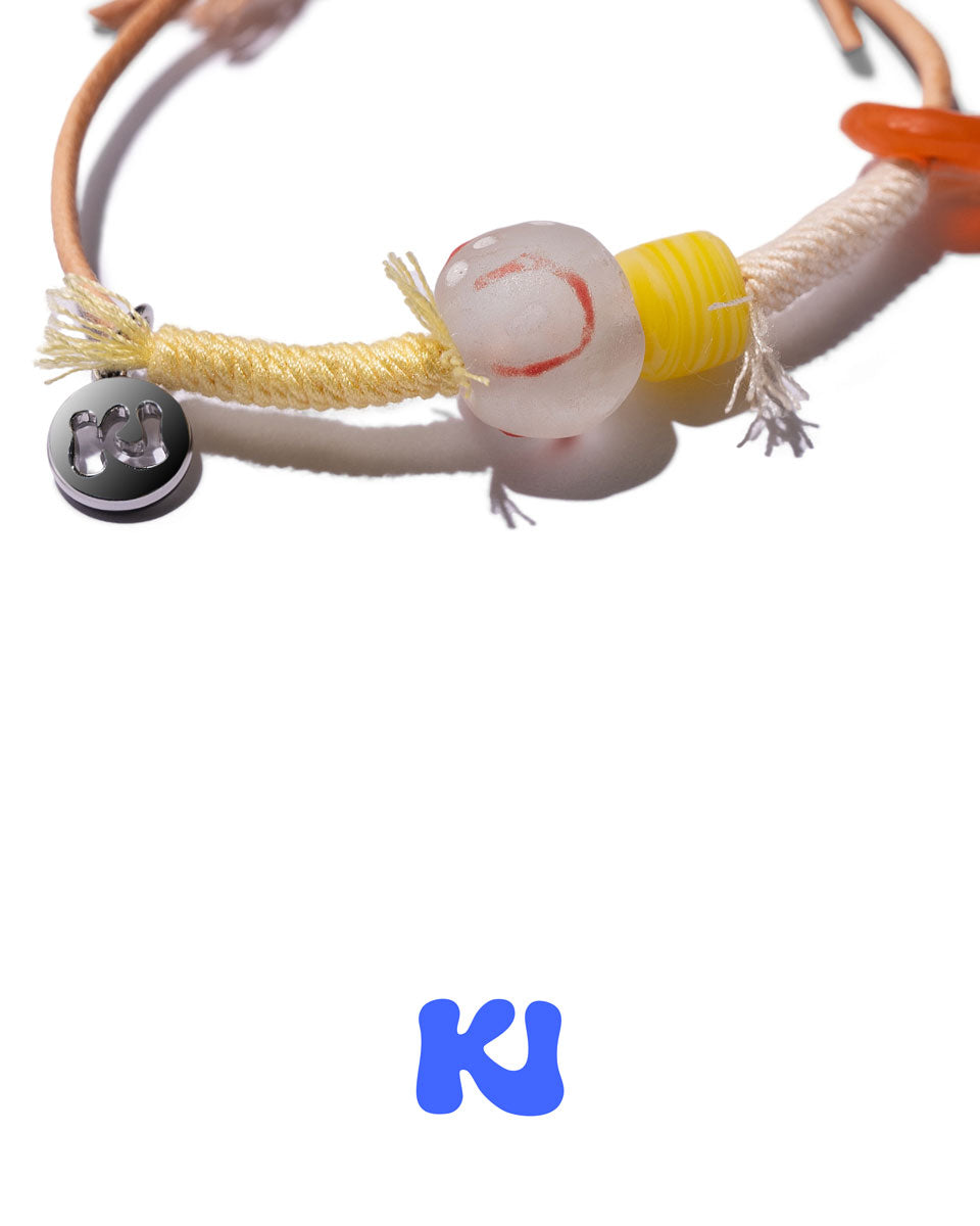 Close-up of multicolor rope bracelet with white beads, yellow ring beads, and orange cord