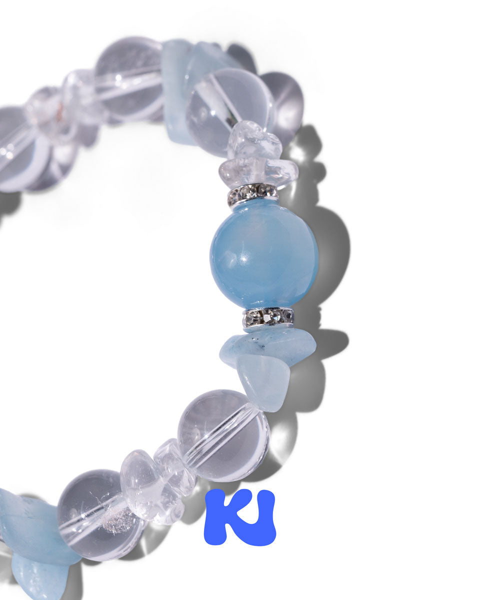 Light blue round bead detail on clear beaded charm bracelet with metal clasp