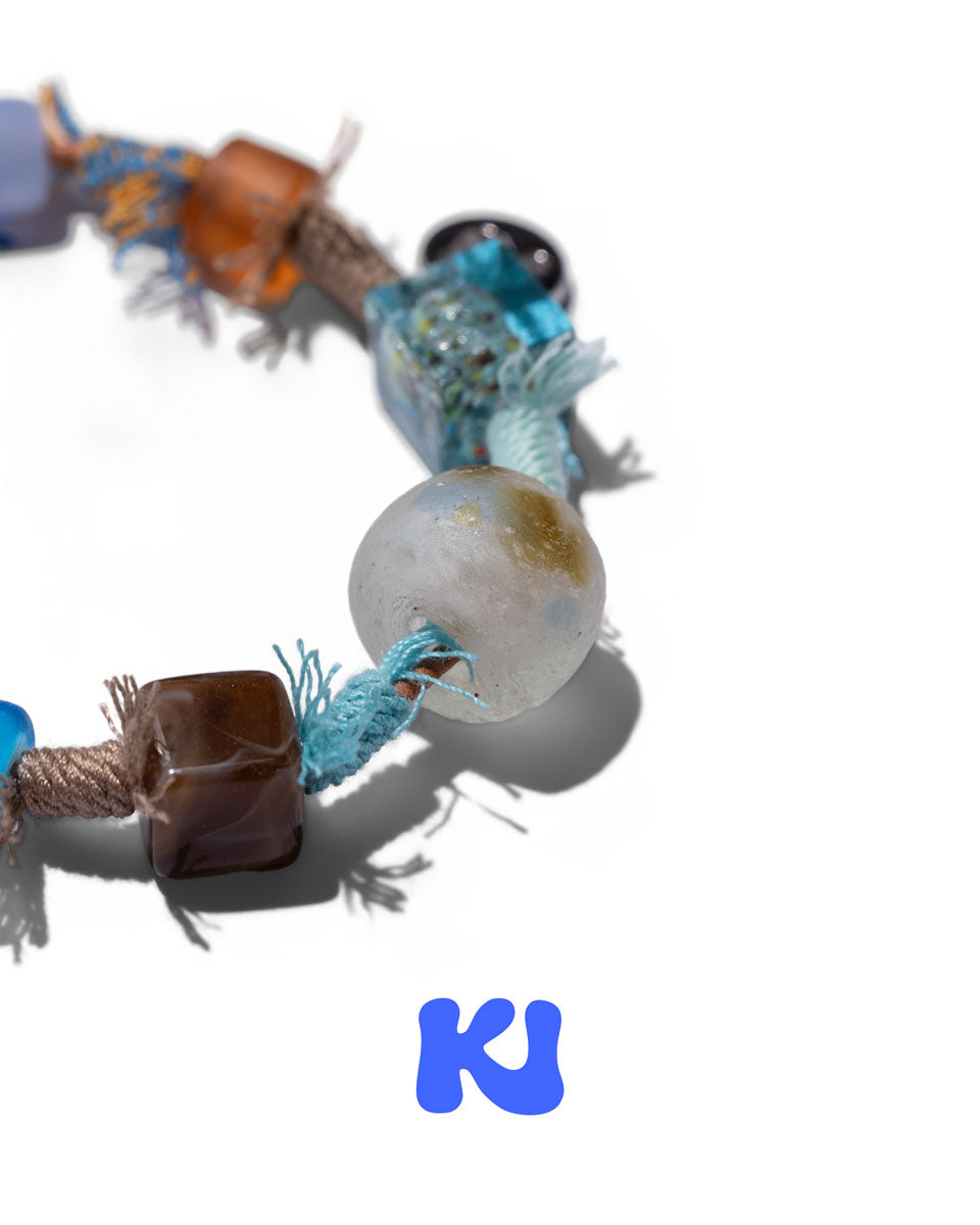 Close-up braided bracelet with light gray round bead and turquoise tassel accents