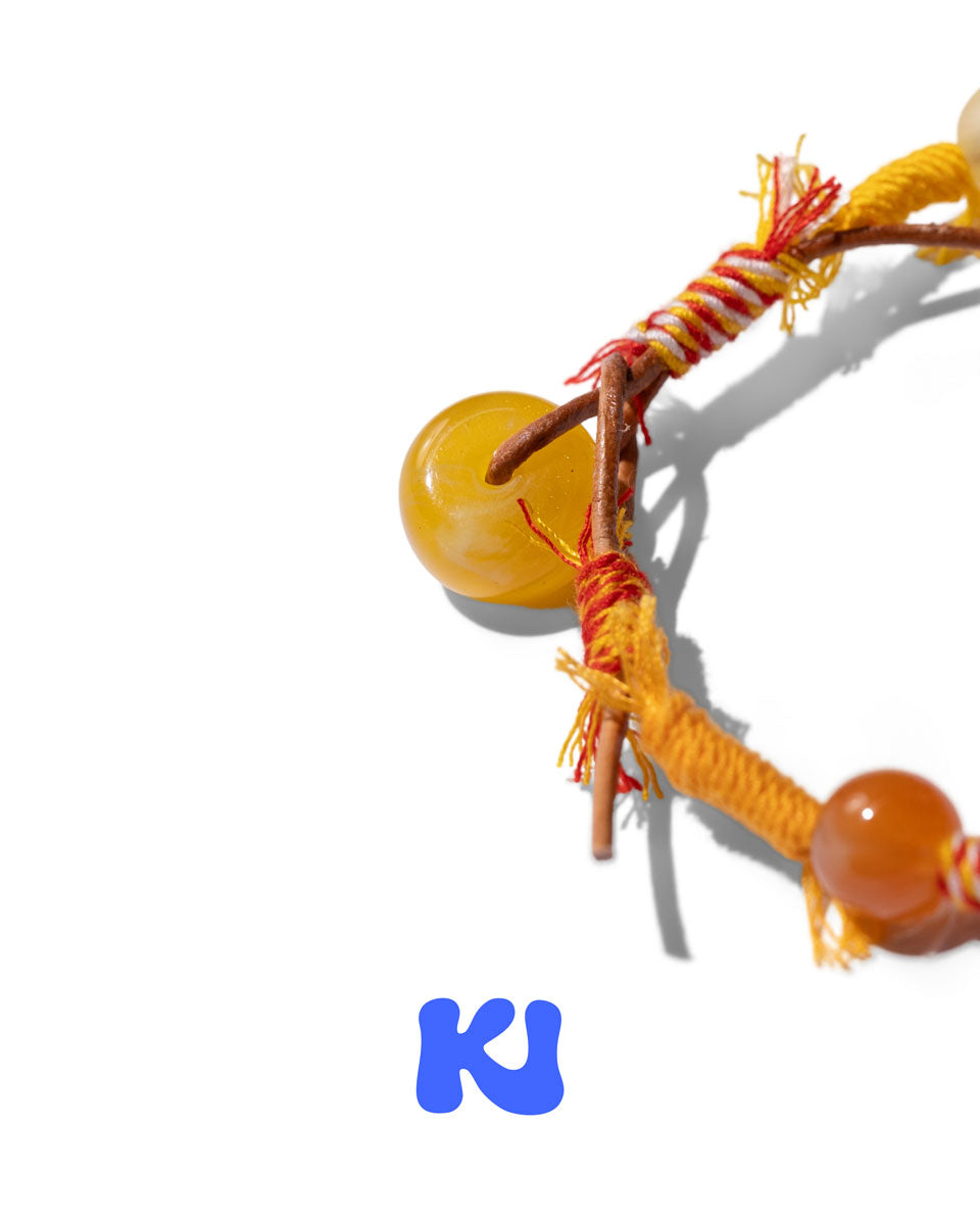 Close-up of braided knot and amber teardrop beads with orange fringe.