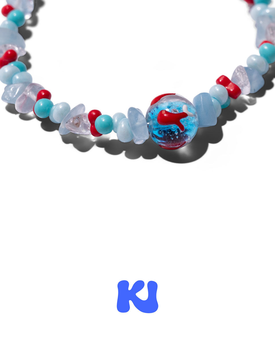 Close-up of beaded bracelet with light blue and red glass beads and blue-red centerpiece