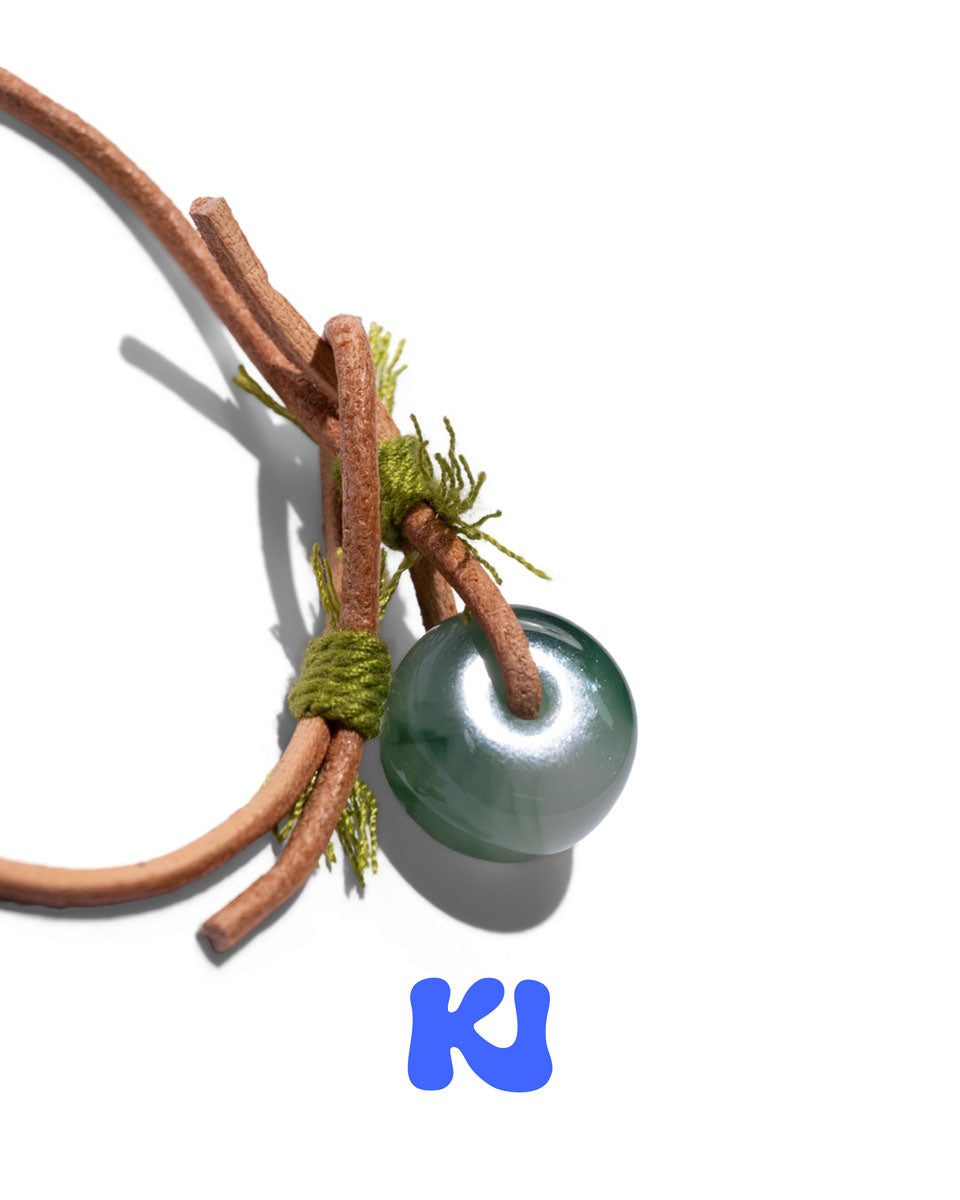 Moss Glade bracelet close-up: green glass bead with braided cord and decorative charm