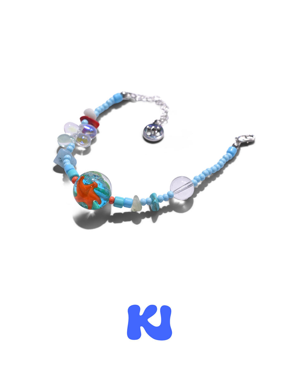Beaded charm bracelet with blue beads, orange centerpiece, silver clasp charm details