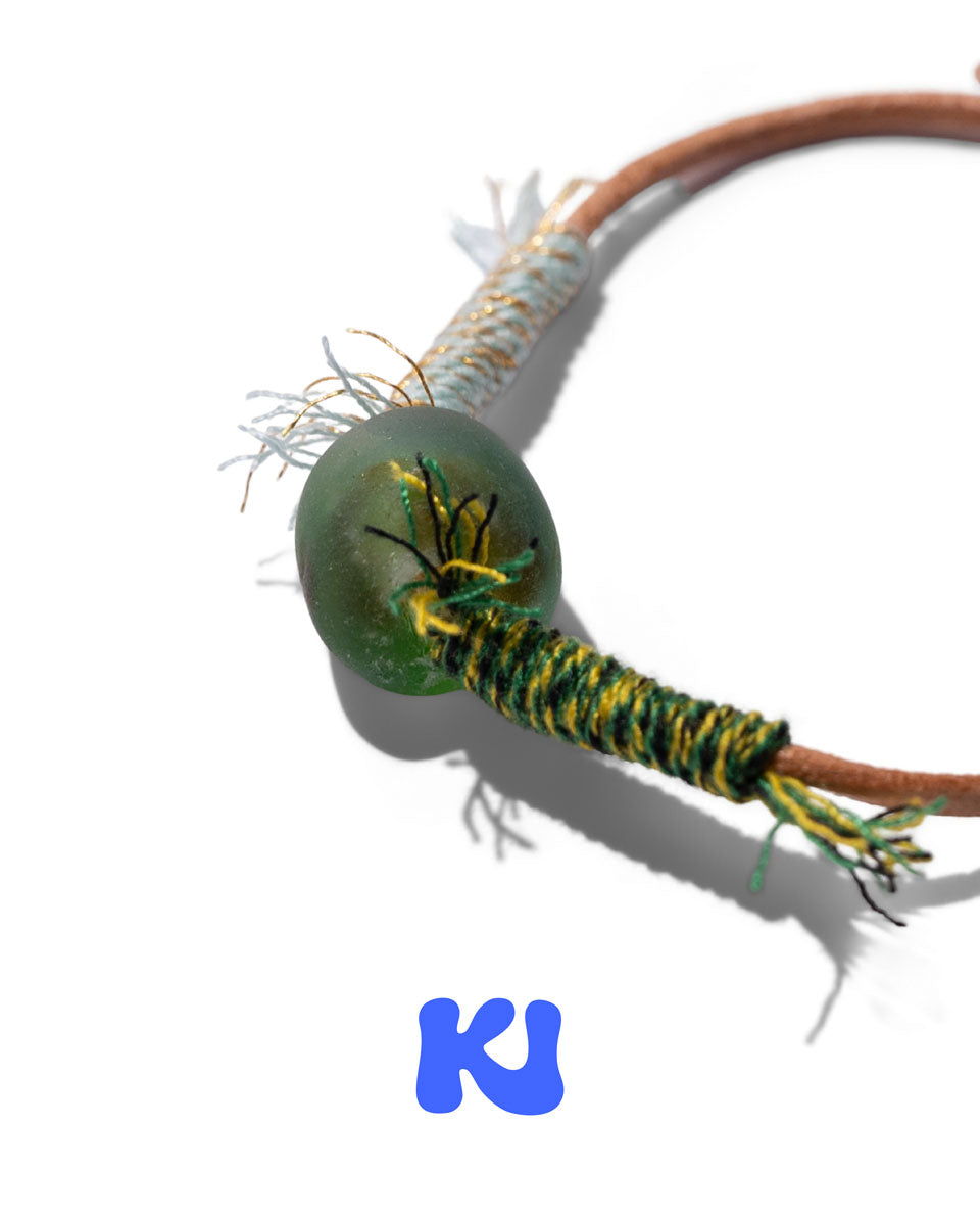 Moss Glade bracelet close-up of green bead on braided cord with yellow stitching