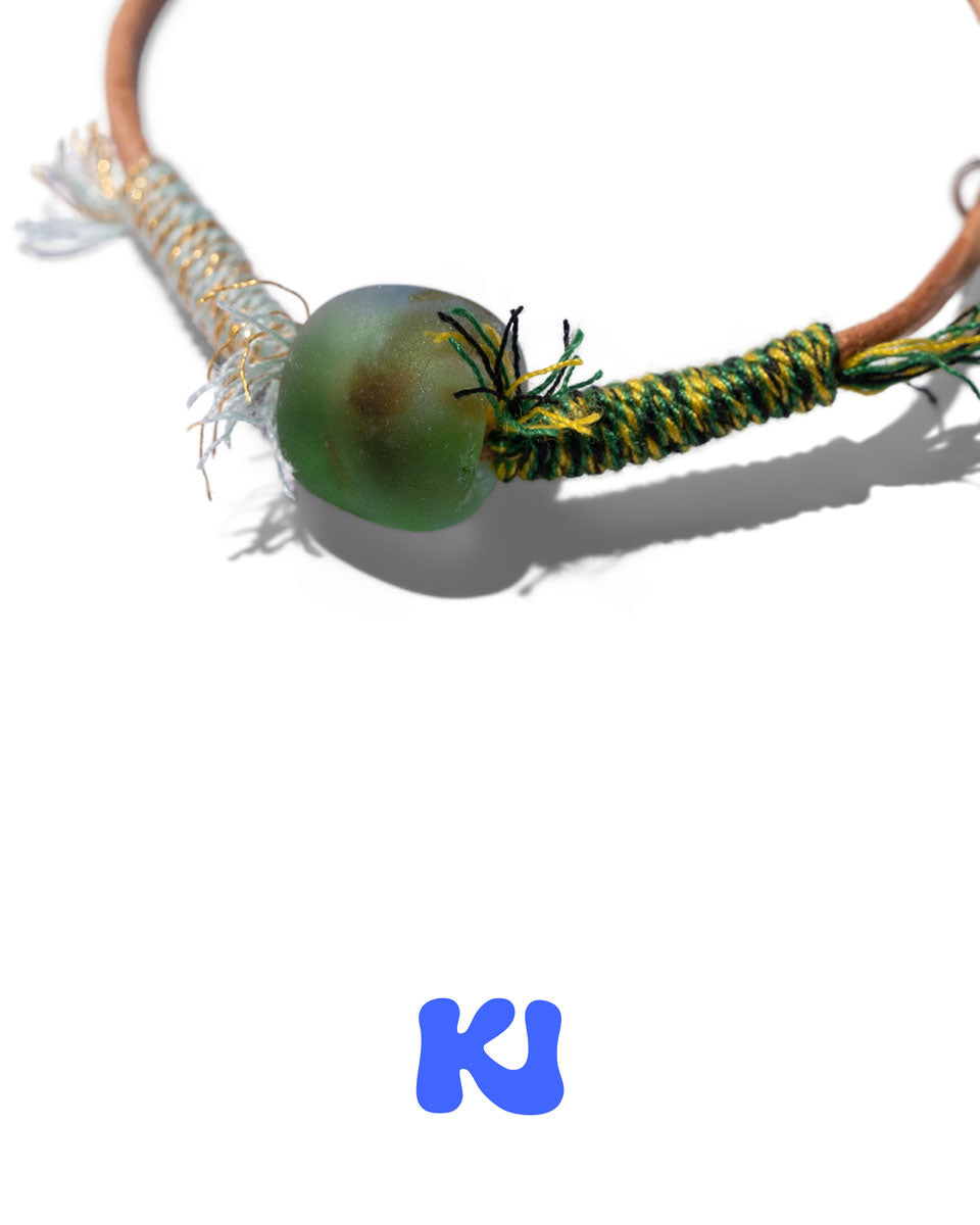Moss Glade bracelet close-up: green bead on braided cord with fringe and string tie